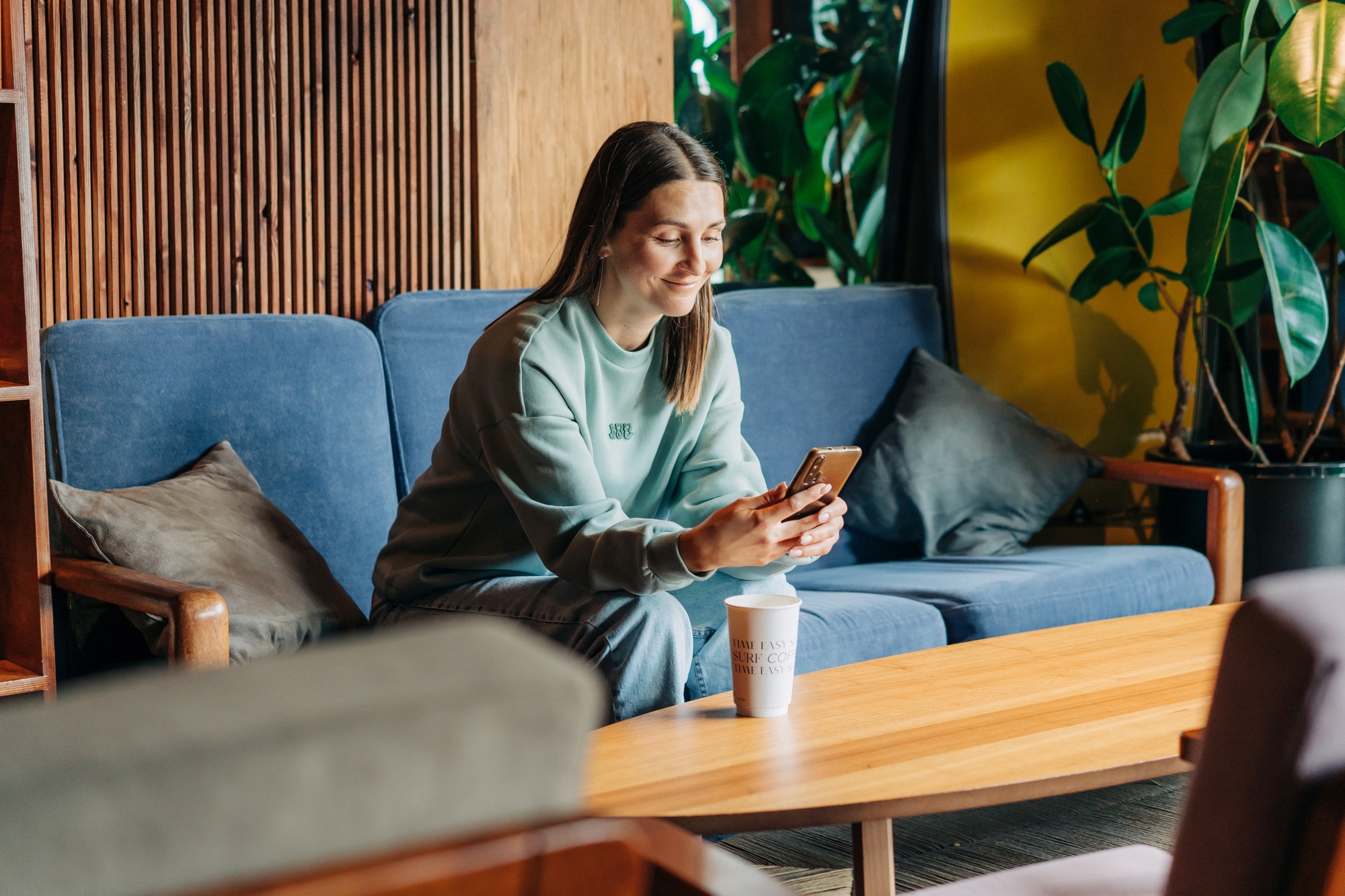 A woman sitting in a coffee shop writes an online message.