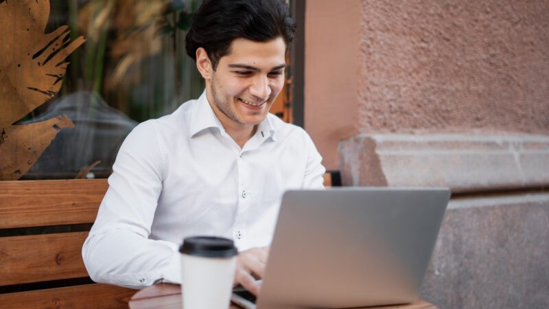 in a cafe uses a laptop writes a message to the mail a manager in an official suit