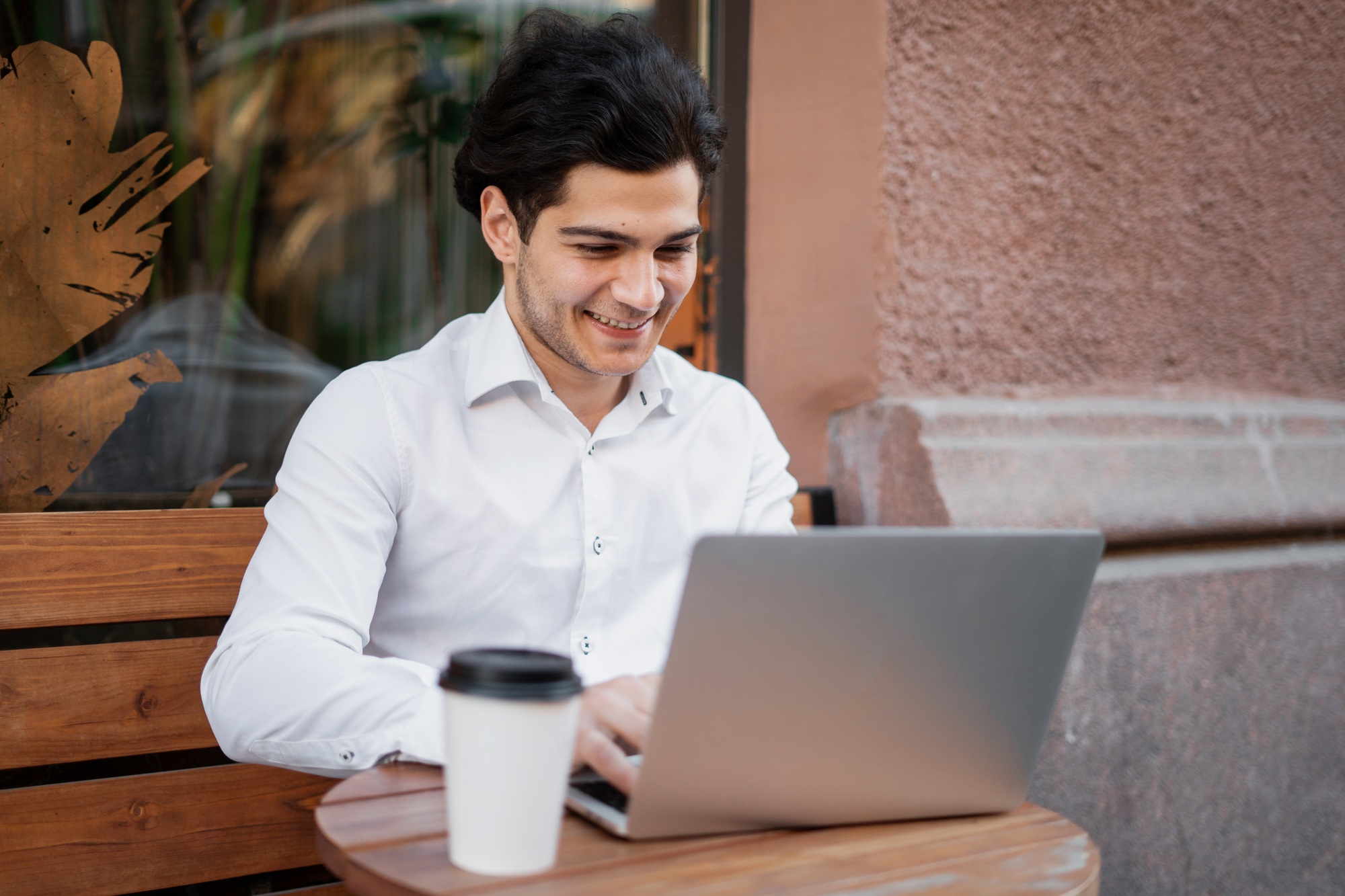 in a cafe uses a laptop writes a message to the mail a manager in an official suit