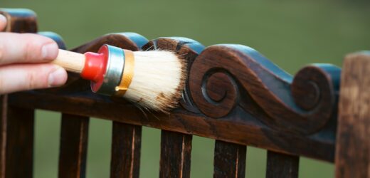 Man painting a wooden chair outdoors, an eco-friendly re-use business.