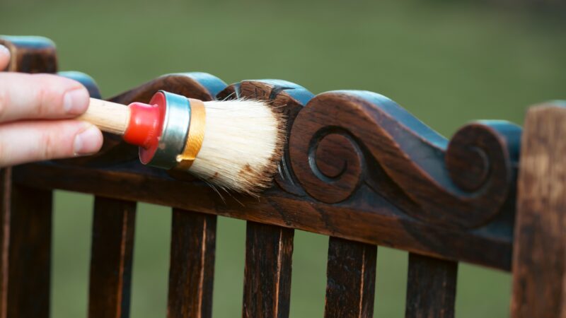 Man painting a wooden chair outdoors, an eco-friendly re-use business.