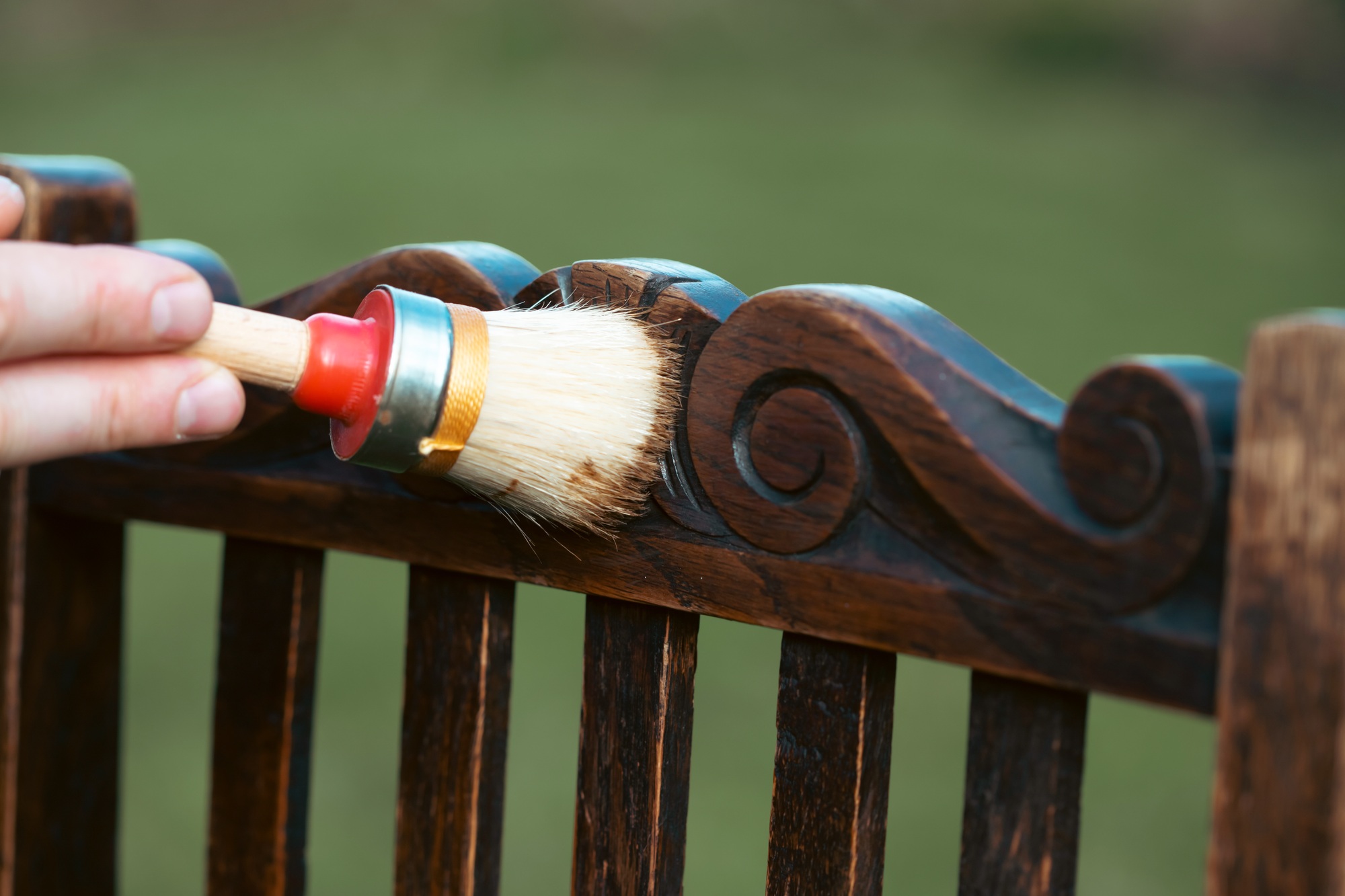 Man painting a wooden chair outdoors, an eco-friendly re-use business.