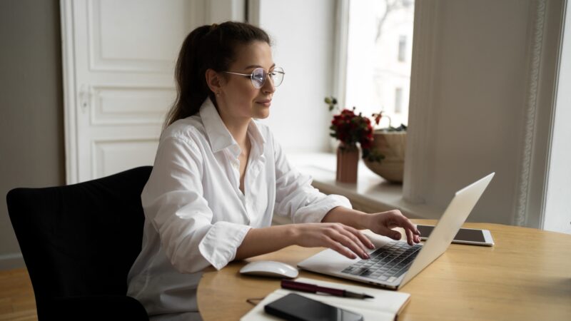 Manager woman with glasses works in the office writes a message to the client on the post