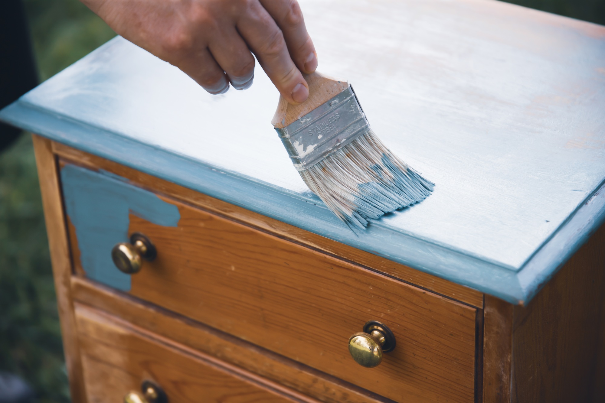 Painting a wooden furniture outdoors, an eco-friendly re-use business.