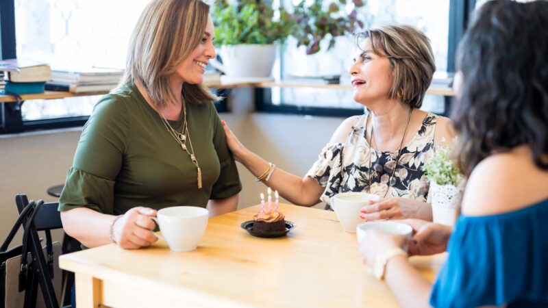 Woman receiving birthday wishes from friends at cafe
