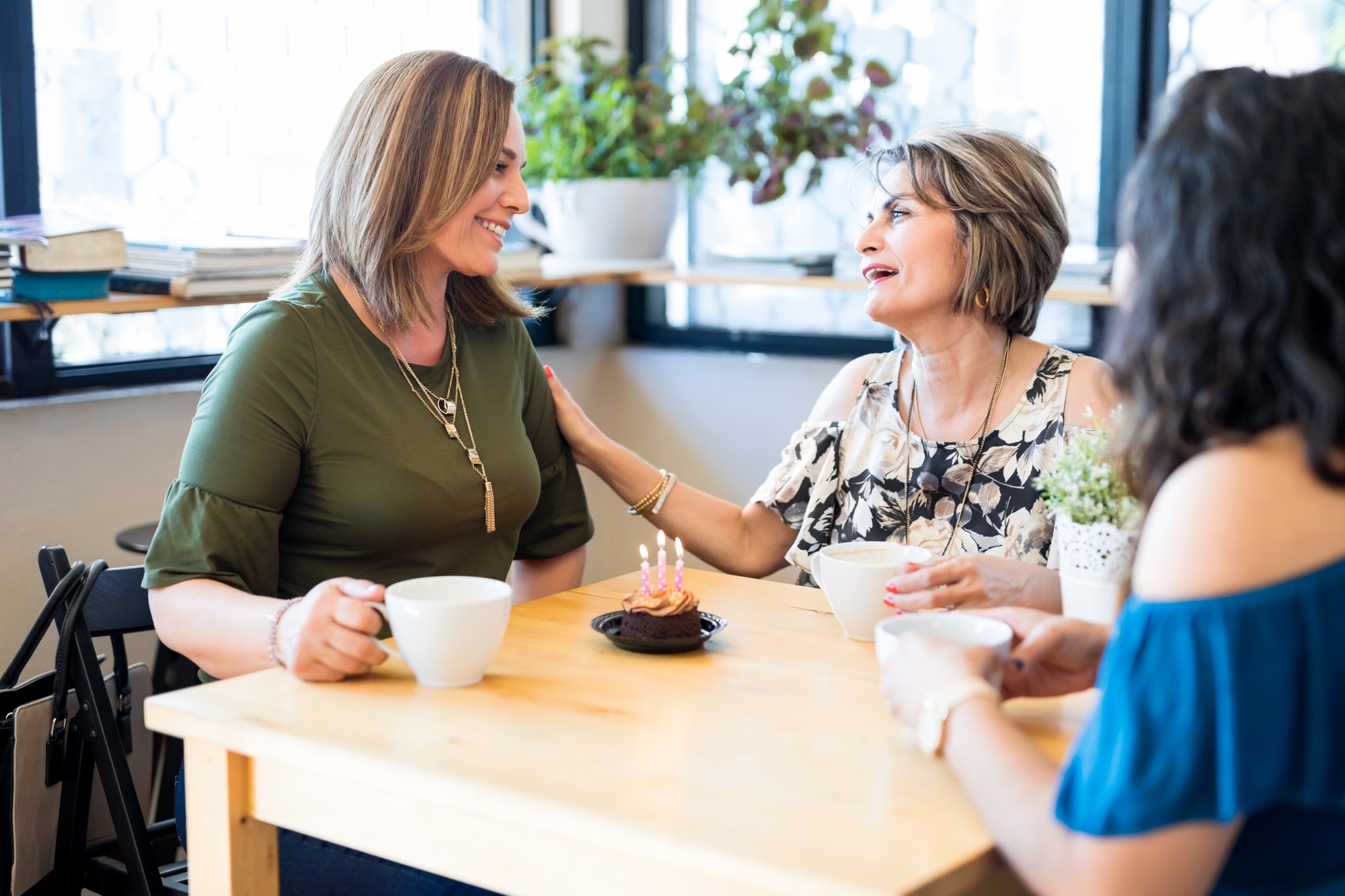 Woman receiving birthday wishes from friends at cafe