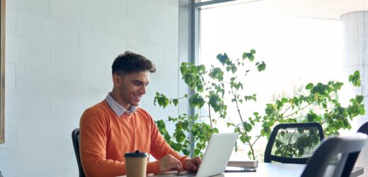 Young Indian student sitting using pc laptop computer at modern college campus.