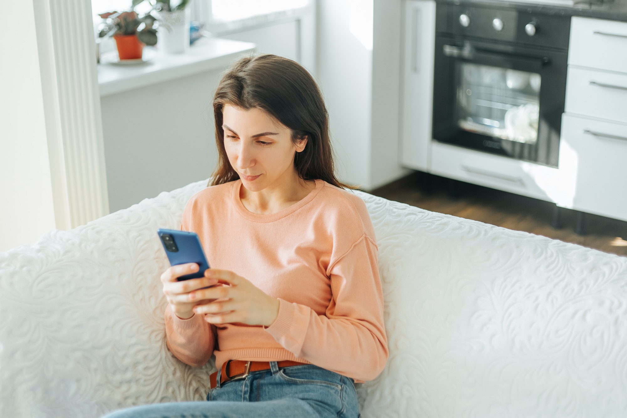 A charming young woman is captured in this photo, sitting on her sofa and browsing