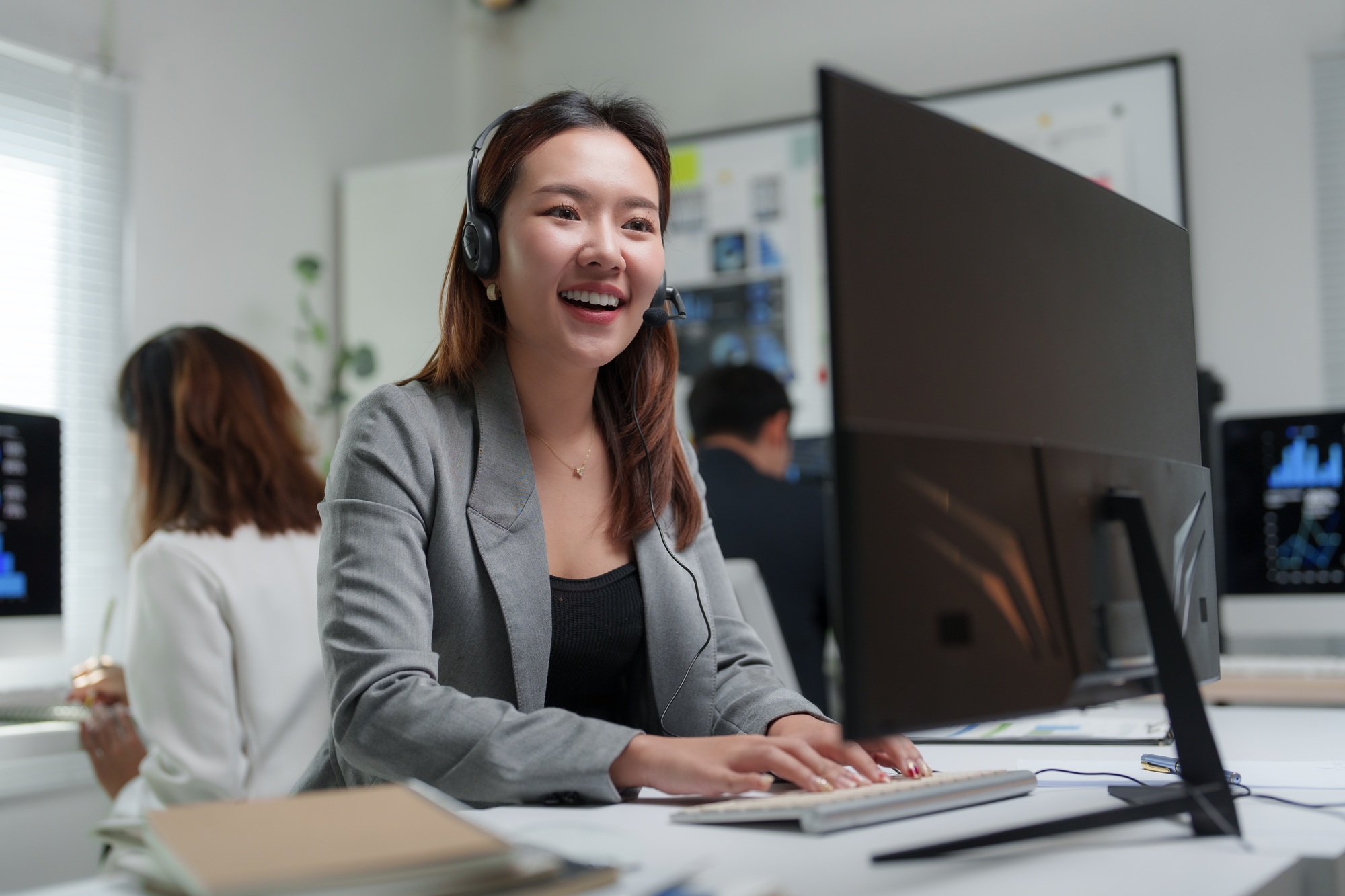 Asian businesswoman wearing headset is working as customer service operator at call center office