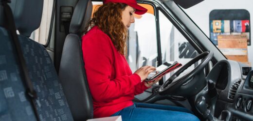 Female delivery driver tracking packages on a tablet in the car