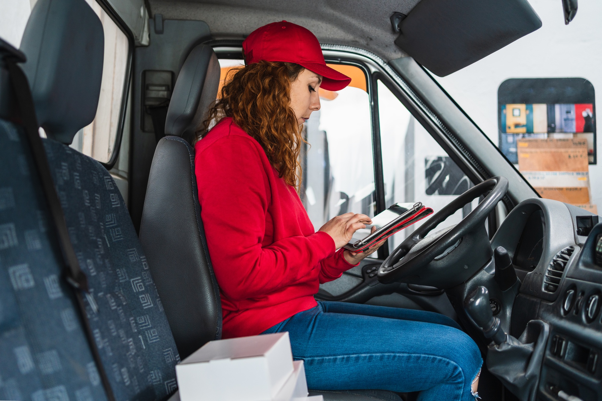 Female delivery driver tracking packages on a tablet in the car