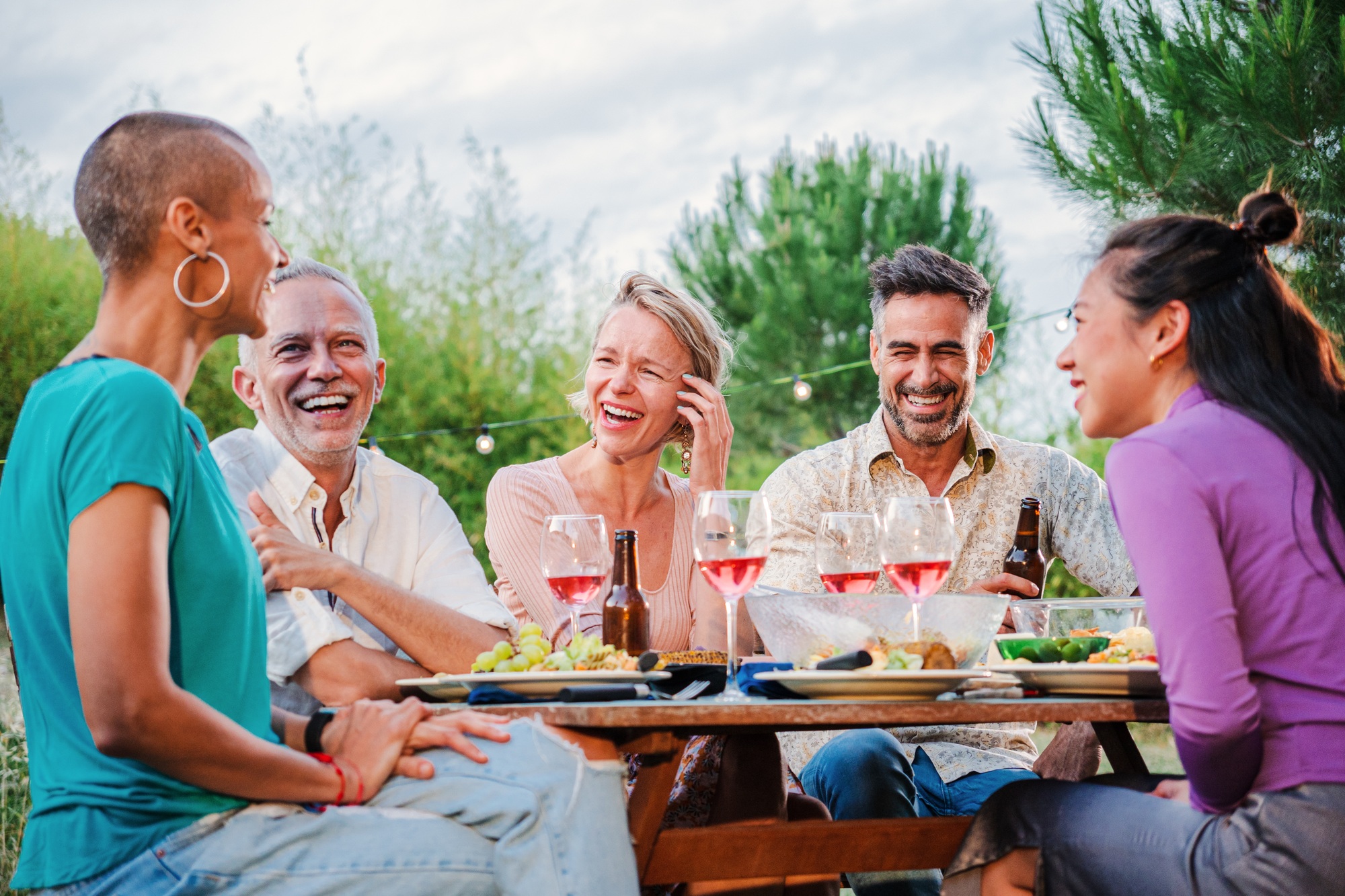 Mature people enjoying at lunch party drinking red wine sitting at dining table at their home