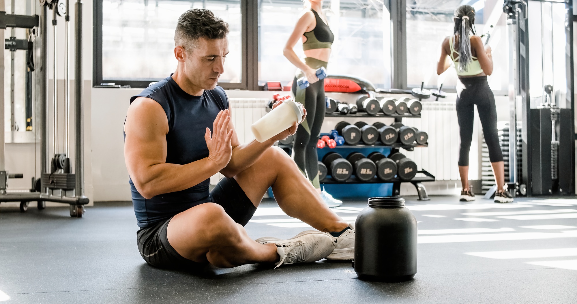 Strong man making protein cocktail in gym