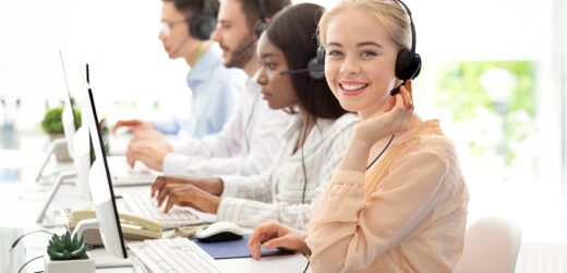 Team of diverse hotline operators with headphones providing service to clients at call center
