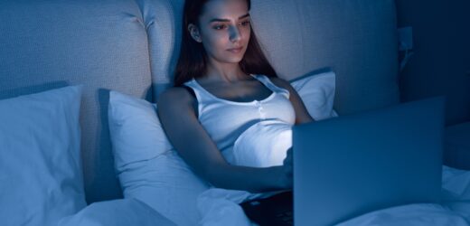 Young woman using laptop in bed at night