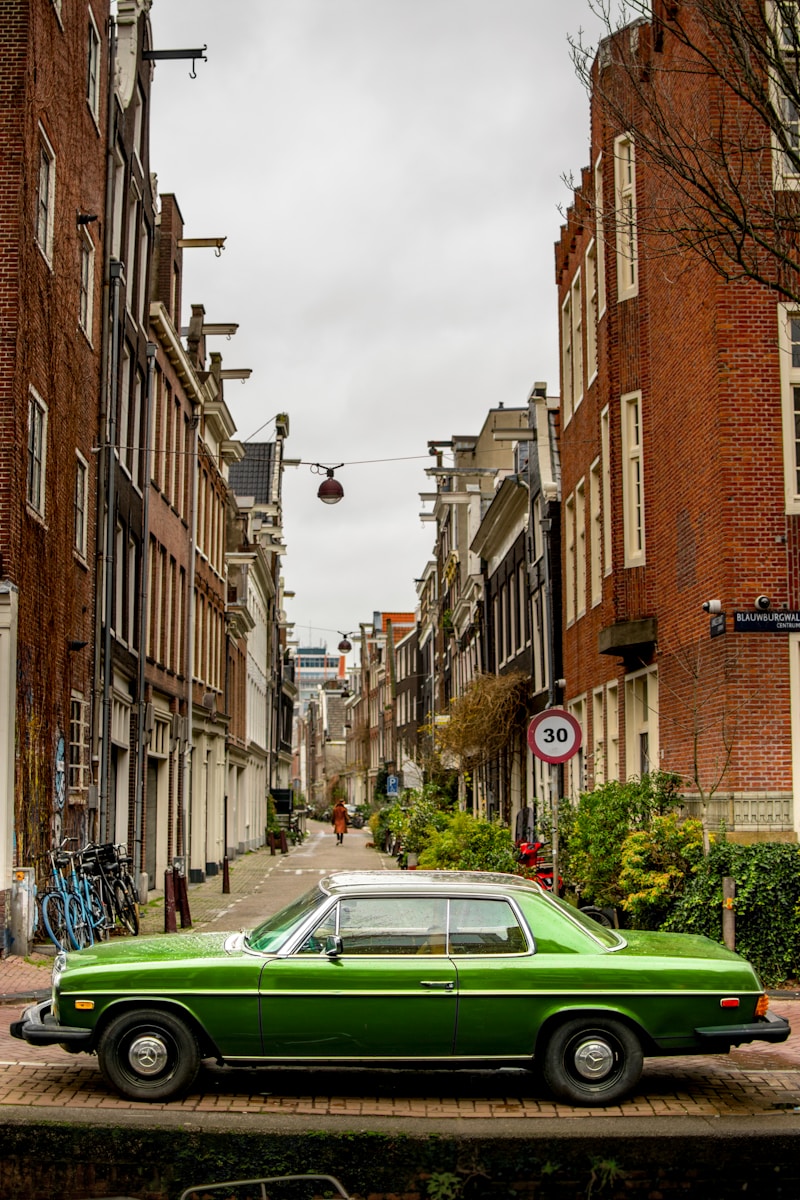 green BMW coupe parked on roadside near buildigns